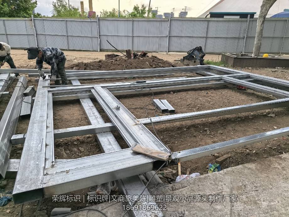 工人正在户外场地焊接大型金属标牌骨架