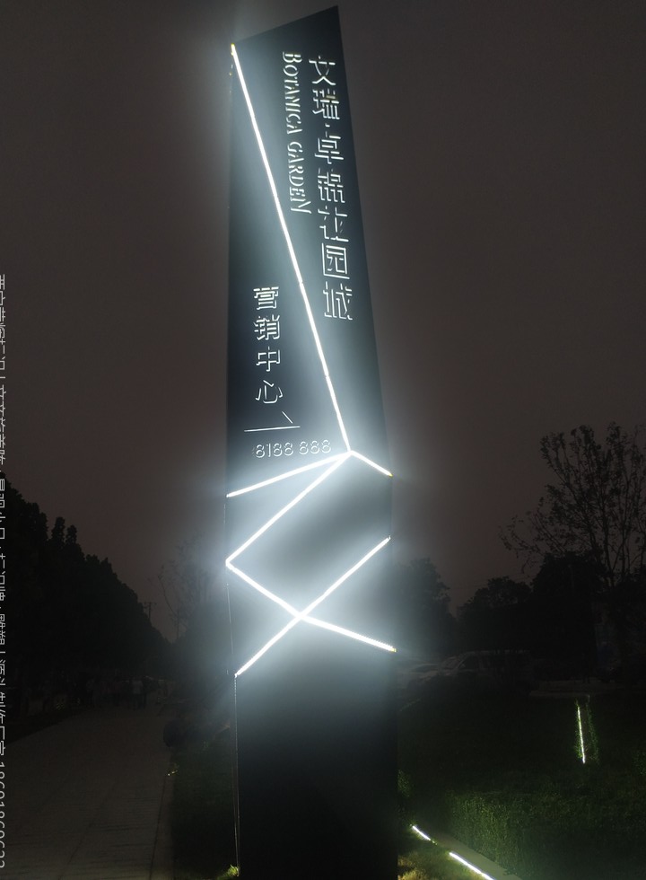 售楼部室外立柱式发光标识牌夜景，白色发光线条造型配竖排项目名称