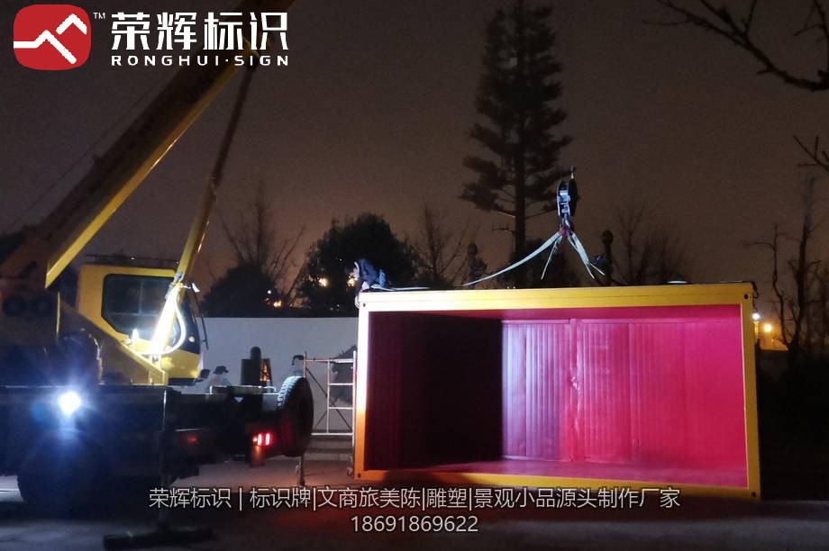 夜间吊车吊装集装箱美陈箱体就位的施工现场