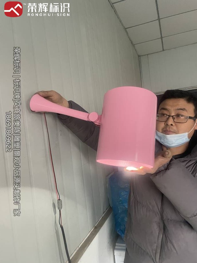 工人手持粉色灯罩通电试亮,暖白光从灯罩开口与内壁均匀透出
