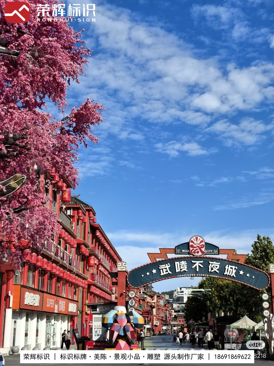 商业街区主入口拱形主标识牌与樱花美陈、彩色几何雕塑实景