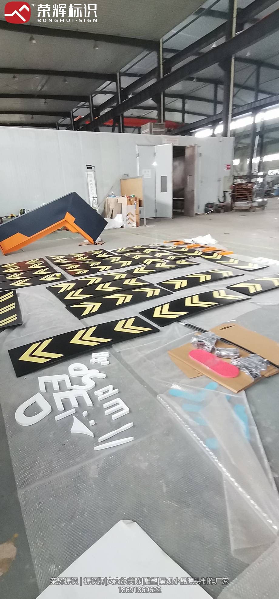 景区标识车间制作照:地面散放的箭头导向牌面板与立体字母配件