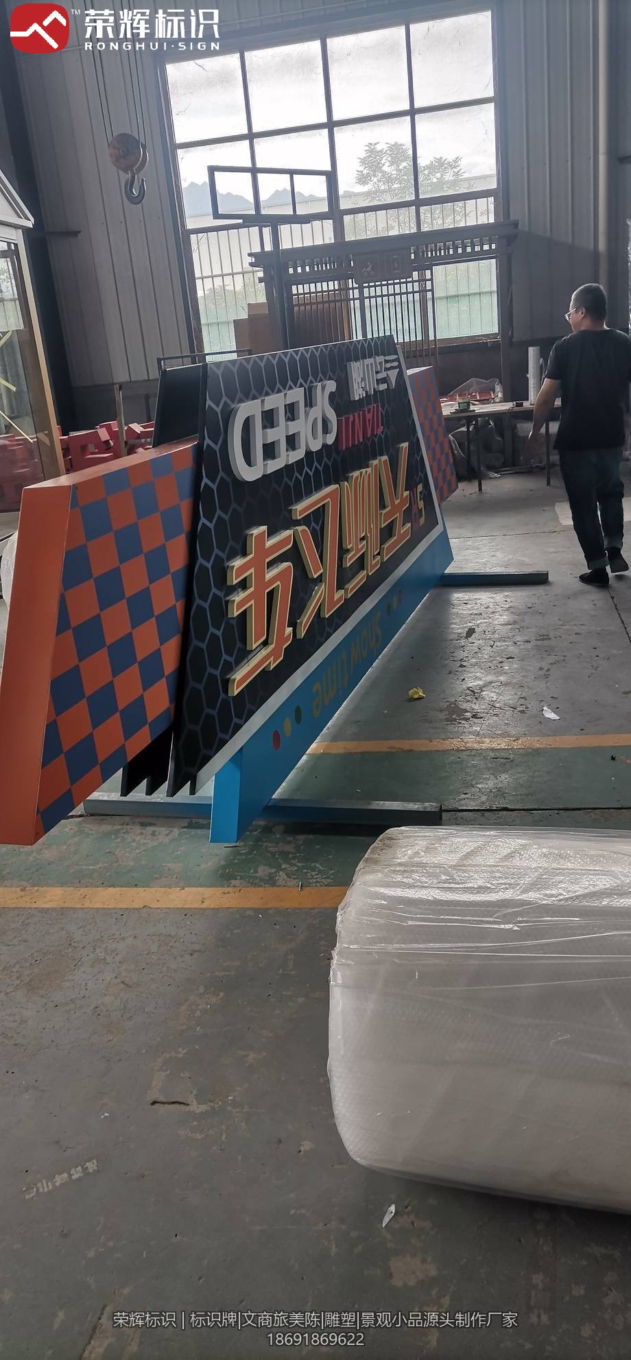 景区景观标识牌车间成品照:黑底配金色立体字与赛车棋盘格元素,组装完毕待出厂